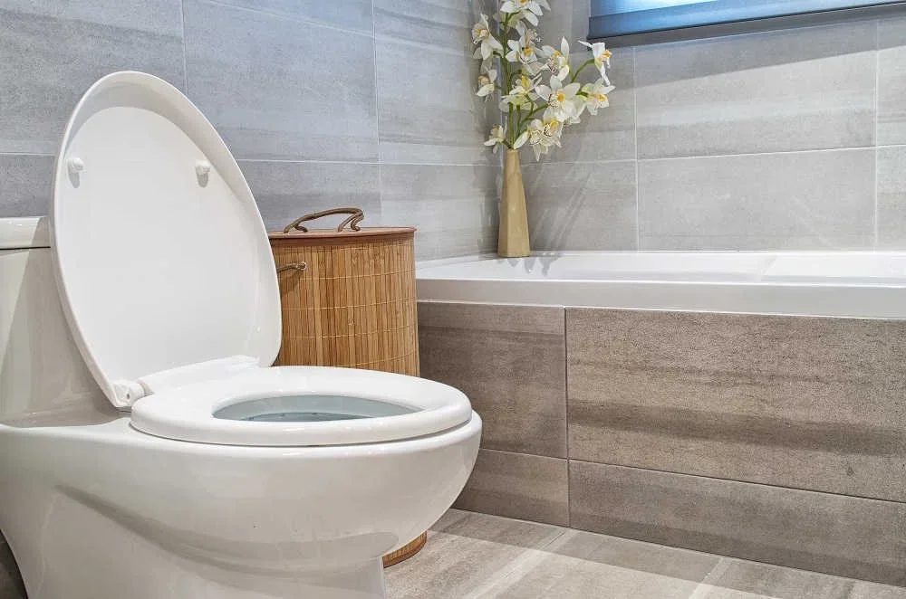 White toilet installed beside a tiled bathroom wall