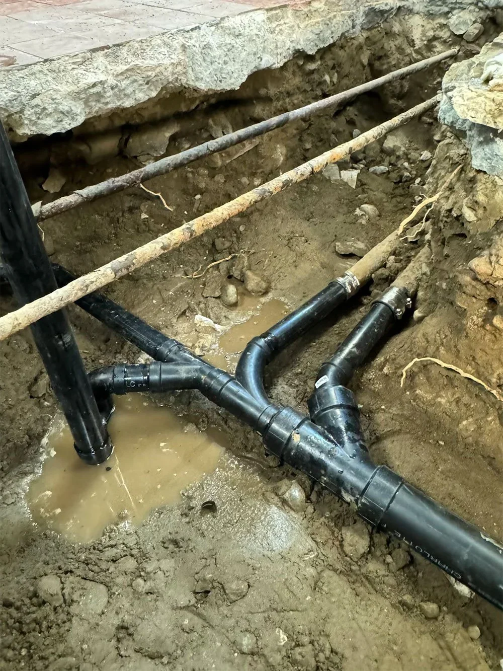 Exposed underground drain pipe connections in an excavated work area