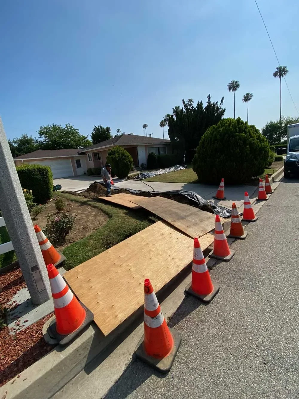Water main excavation work marked by traffic cones beside a road